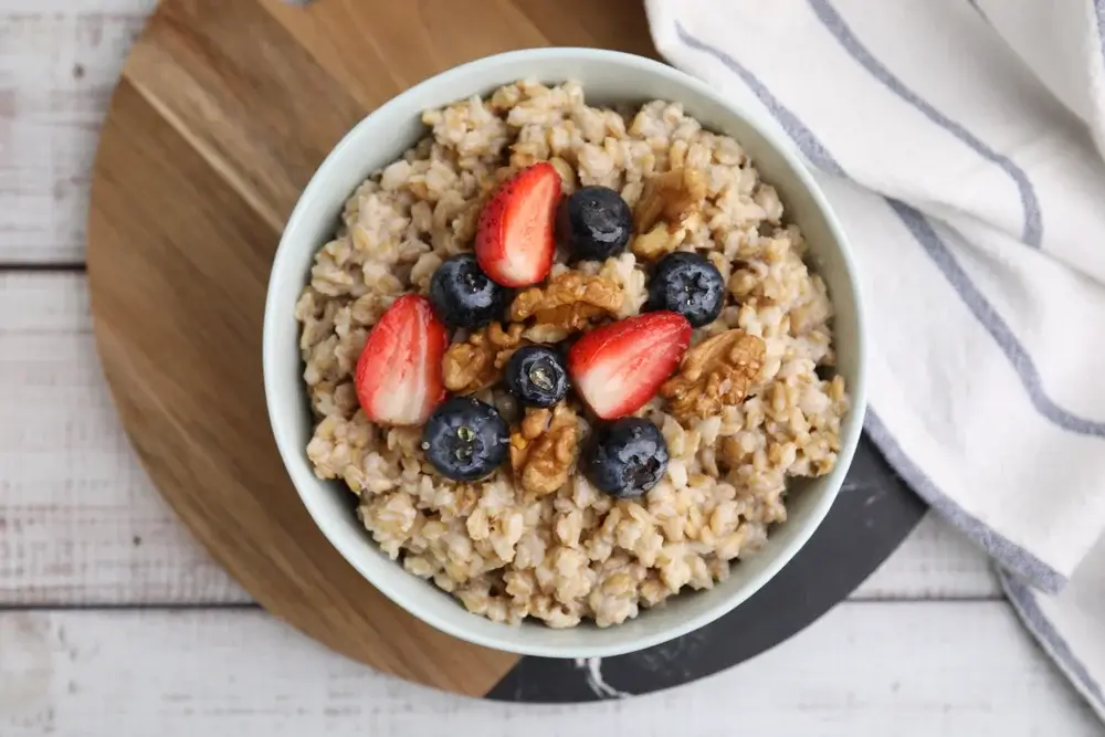 Oatmeal topped with berries and a spoonful of chopped walnuts